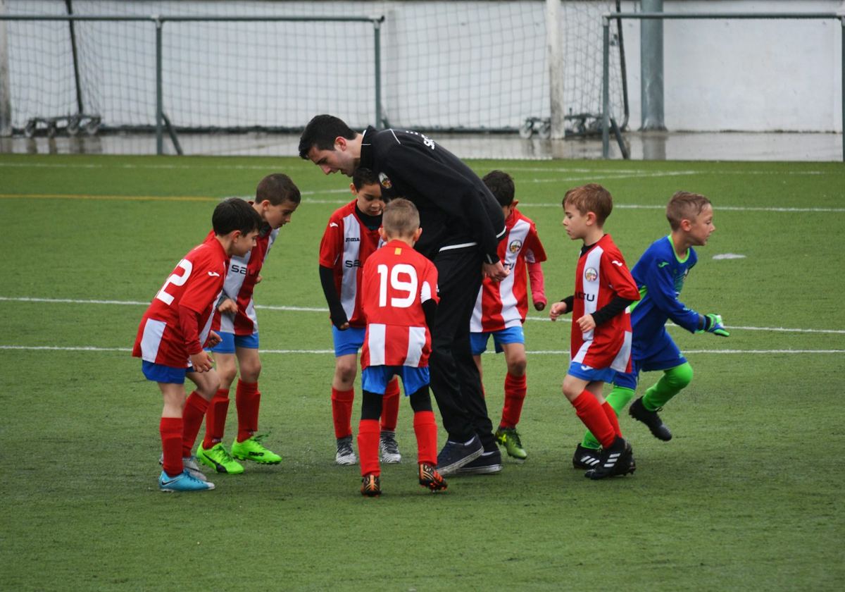 コーチの話を聞くサッカースクールの子どもたち